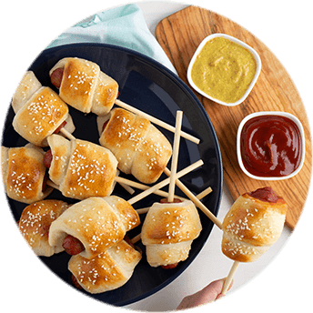 A plate full of mini corn dogs on sticks, with dipping sauces